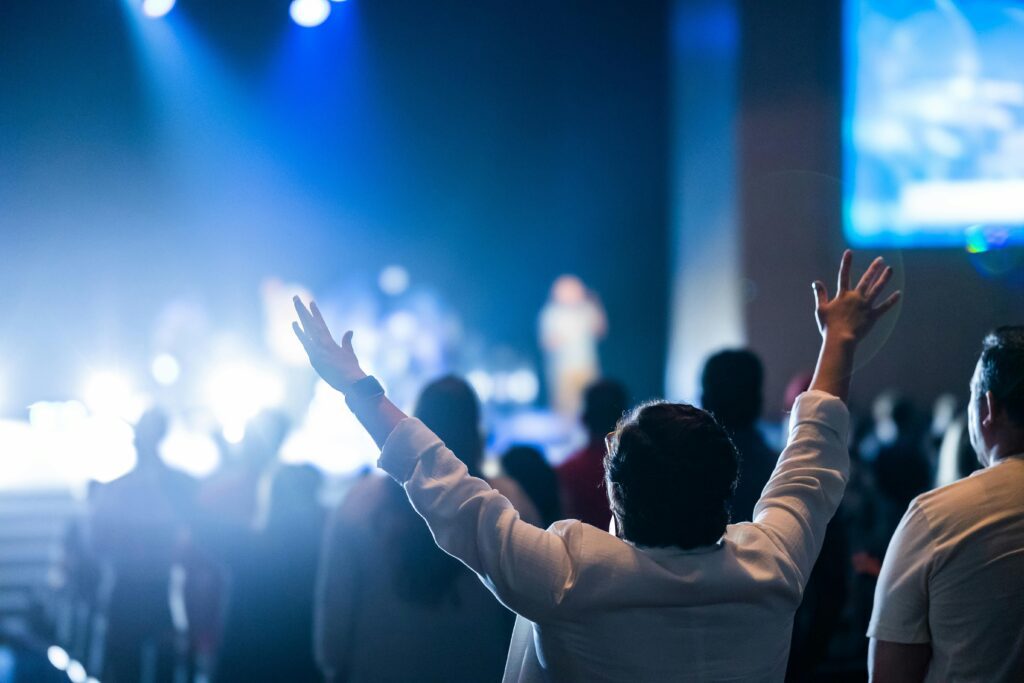 Why is Praise and Worship Music so Horribly Bad? 2 Contemporary worship service with stage lights and raised hands showing concert-style performance atmosphere
